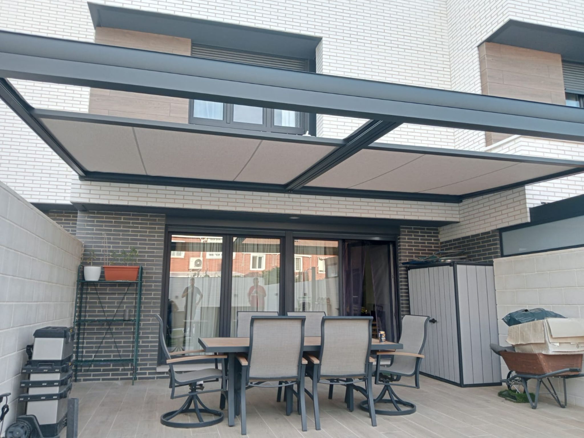 Pérgola con cubierta de lona instalada sobre zona de comedor en patio trasero de vivienda de ladrillo claro